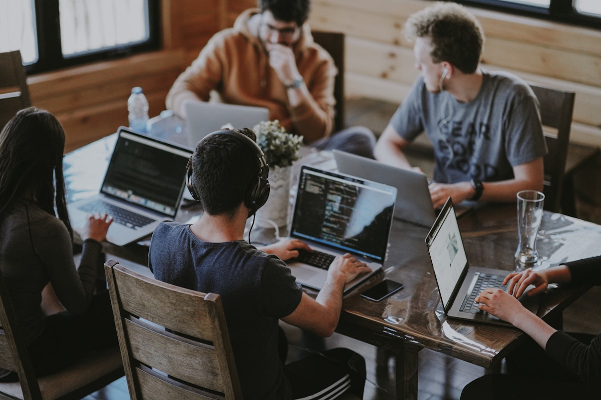 Group of people working together at a table with laptops